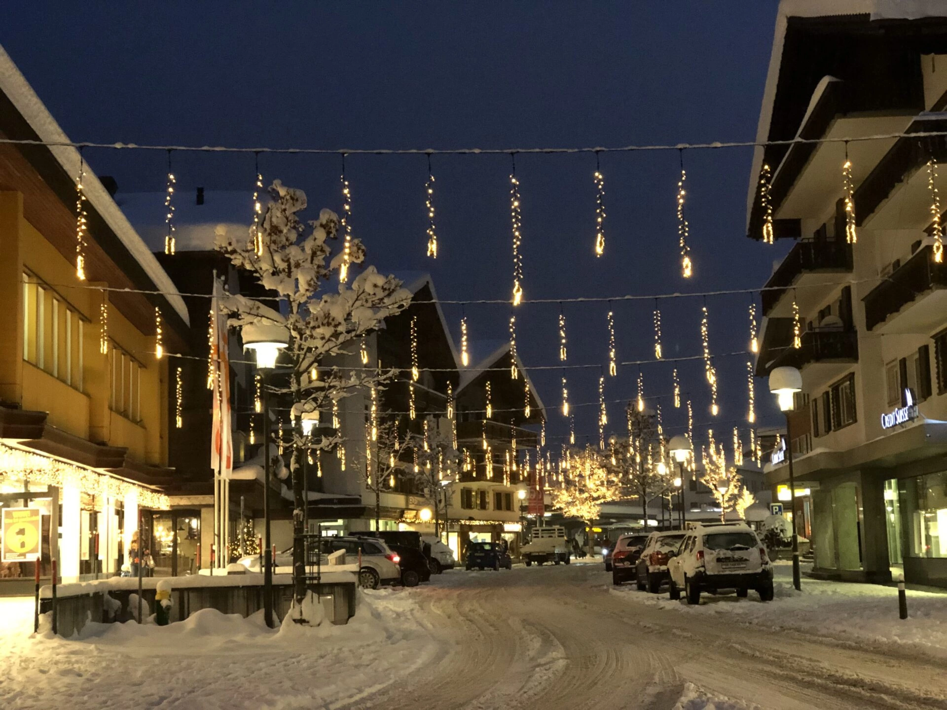Beleuchtete Dorfstrasse in Klosters bei Nacht mit festlicher Beleuchtung und alpiner Bergkulisse