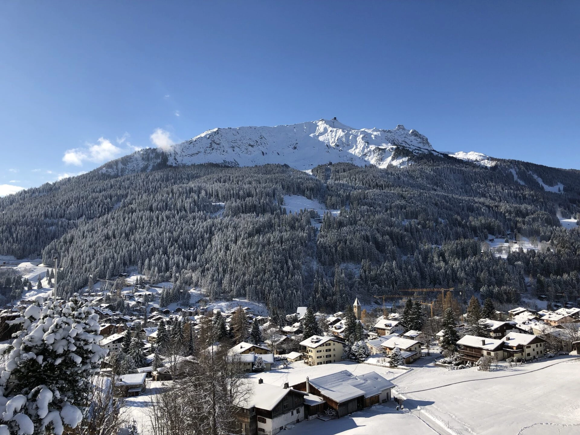 Verschneites Bergdorf Klosters in Graubünden mit Blick auf Häuser und umliegende Alpen im Winter